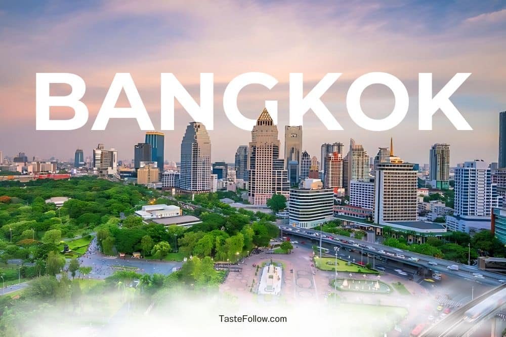 A vibrant cityscape of Bangkok at twilight, blending modern skyscrapers with lush greenery. The skyline showcases diverse architecture under a pink and blue sky. "BANGKOK" is prominently displayed in large white letters across the top, hinting at the natural attractions in Bangkok. Watermarked with "TasteFollow.com" at the bottom center.